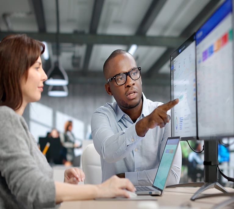 Business professionals reviewing integrated applications, workflow data and connected business systems on multiple screens.