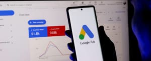 Google Ads dashboard and campaign performance metrics displayed alongside a mobile device showing the Google Ads platform.